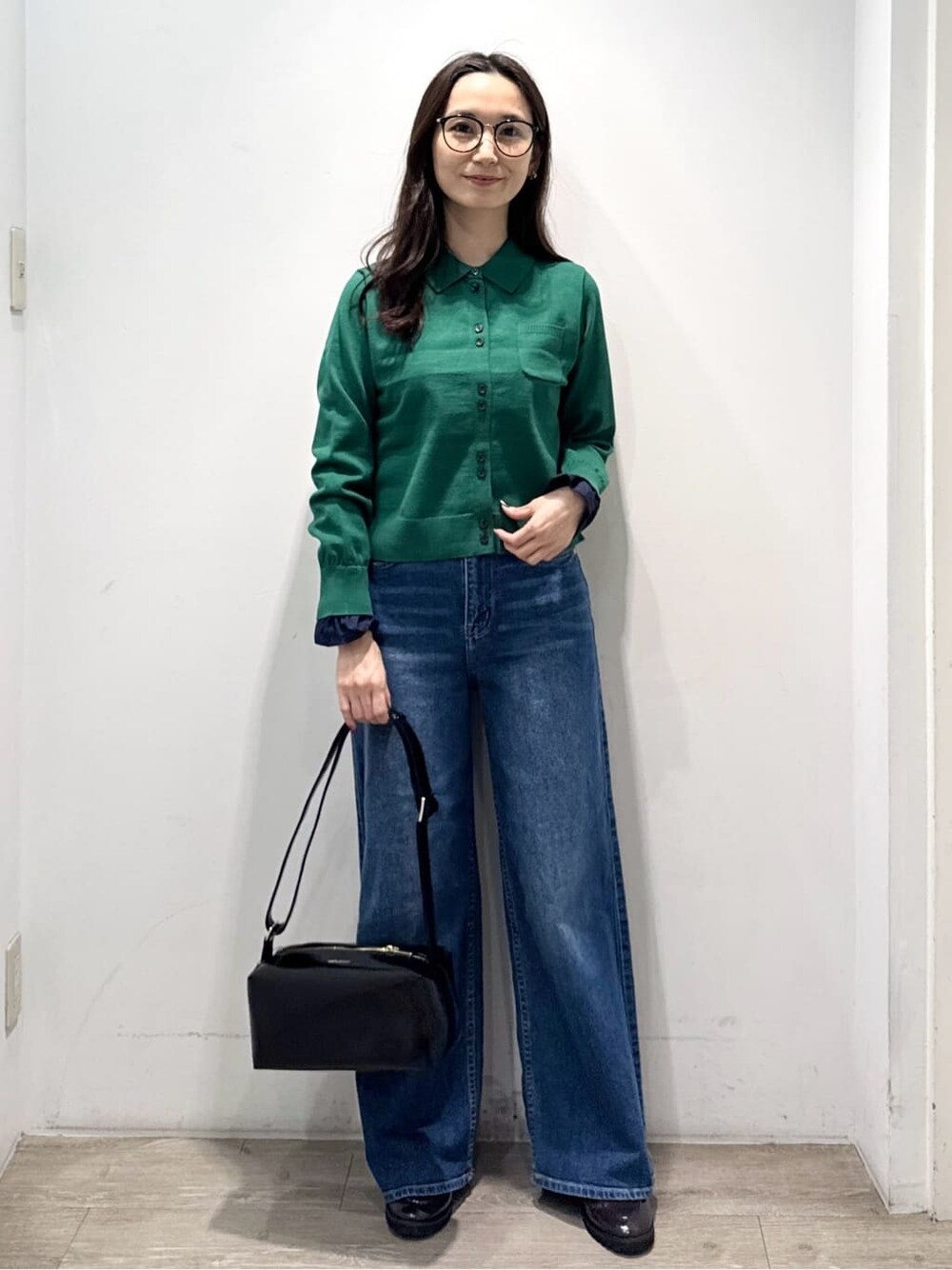 グリーン系のニット/セーター、ブルー系のデニムパンツ、ブラック系のショルダーバッグを着用したレディースの秋コーディネートの3枚目の写真