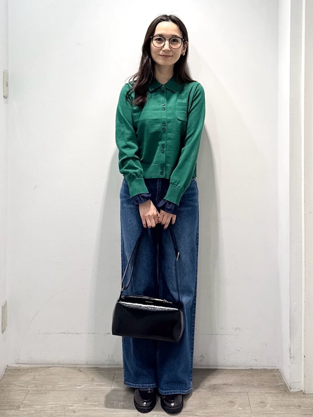 グリーン系のニット/セーター、ブルー系のデニムパンツ、ブラック系のショルダーバッグを着用したレディースの秋コーディネートの5枚目の写真