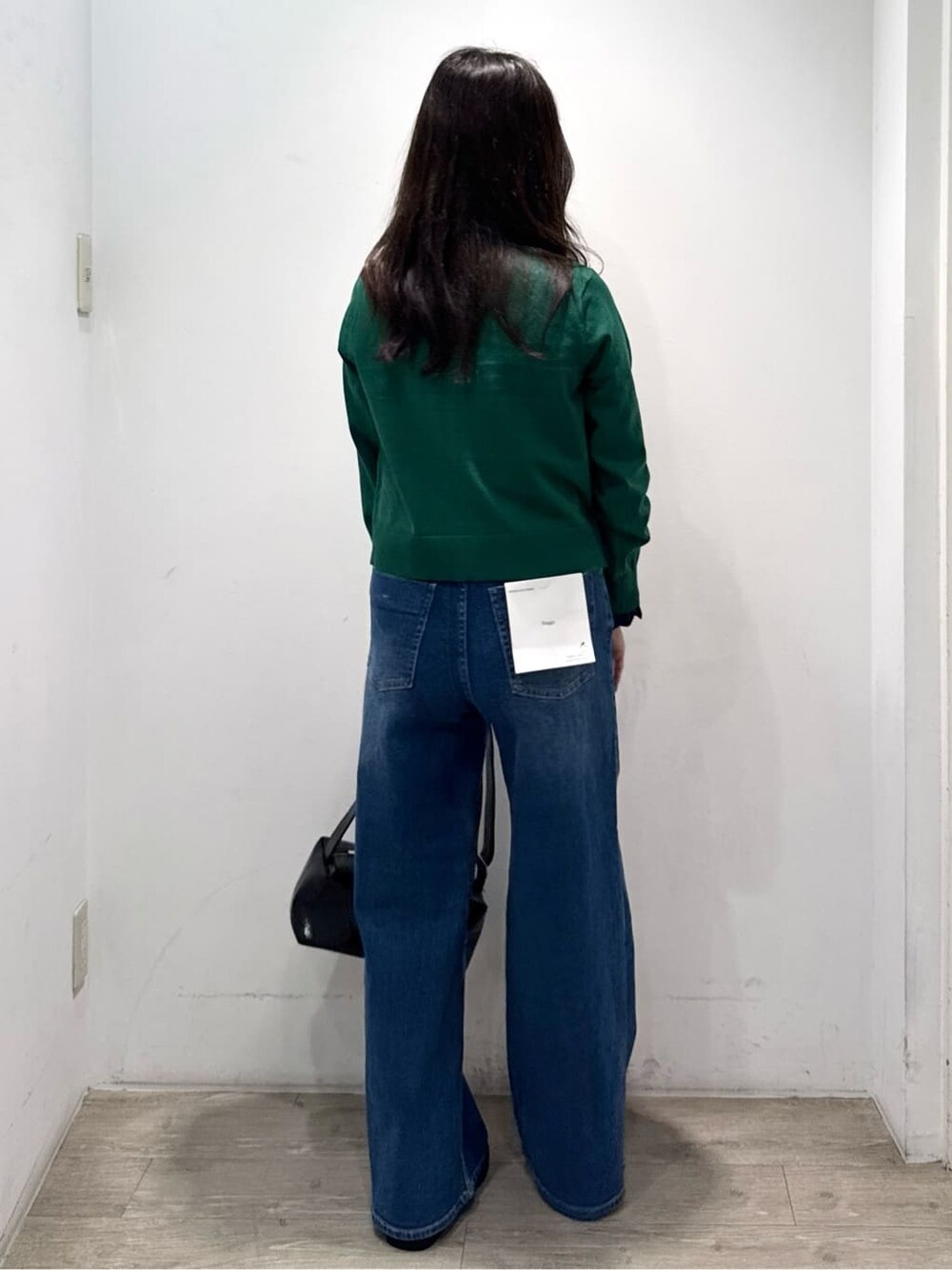 グリーン系のニット/セーター、ブルー系のデニムパンツ、ブラック系のショルダーバッグを着用したレディースの秋コーディネートの8枚目の写真
