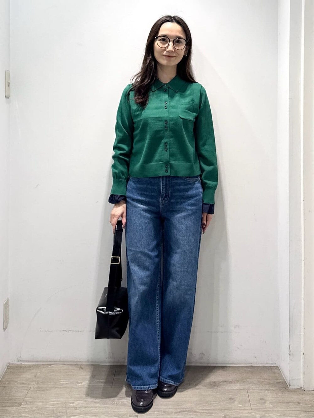 グリーン系のニット/セーター、ブルー系のデニムパンツ、ブラック系のショルダーバッグを着用したレディースの秋コーディネートの2枚目の写真