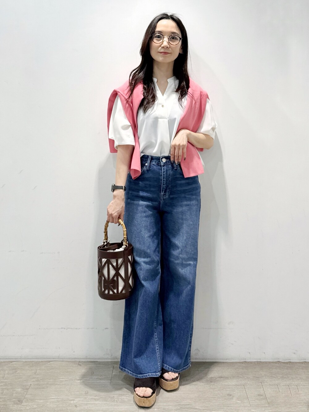 ブルー系のデニムパンツ、ホワイト系のシャツ/ブラウス、ブラウン系のハンドバッグを着用したレディースの春コーディネートの2枚目の写真
