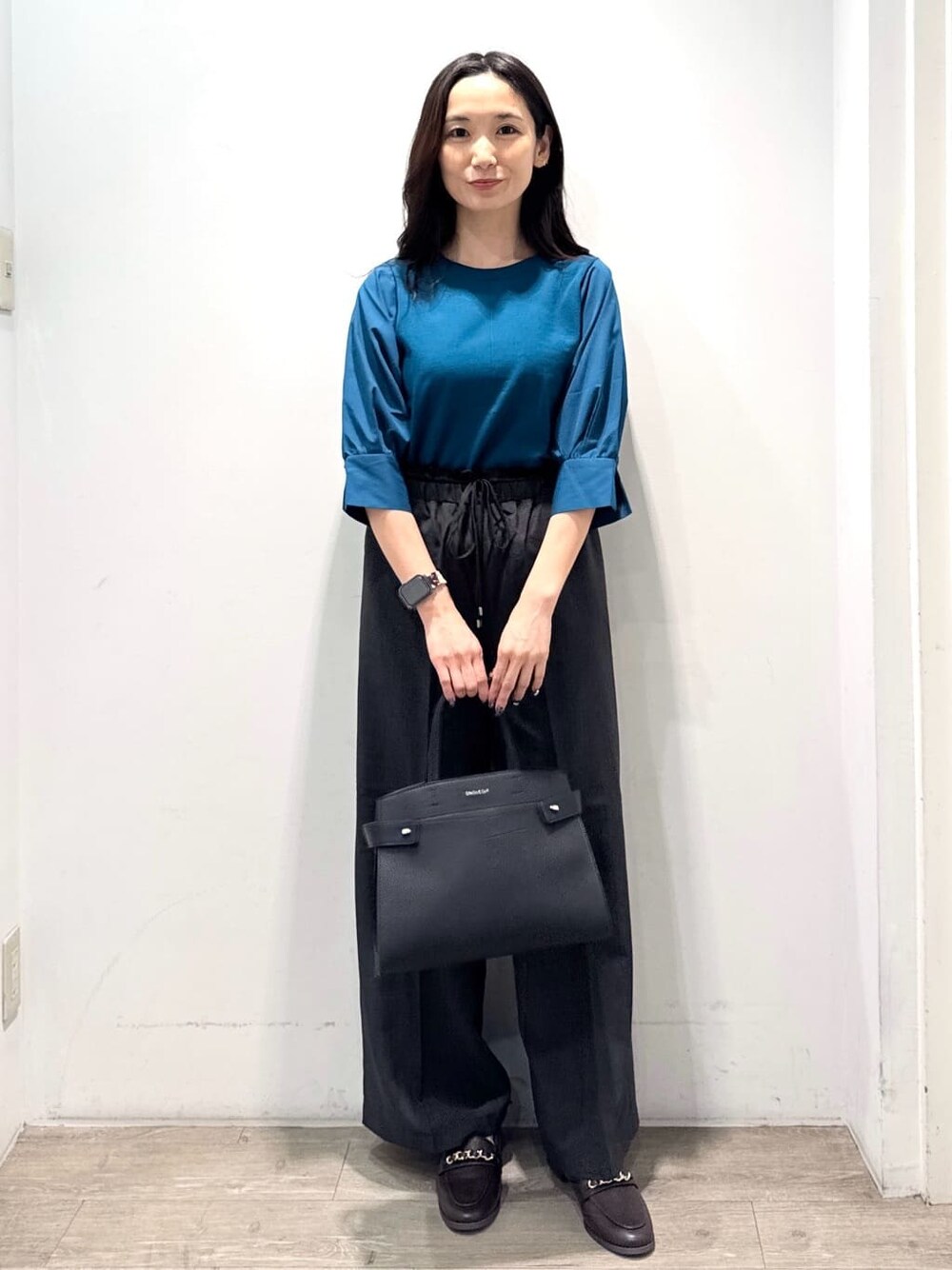 ブルー系のニット/セーター、グレー系のその他パンツ、ブラック系のショルダーバッグを着用したレディースの秋コーディネートの4枚目の写真