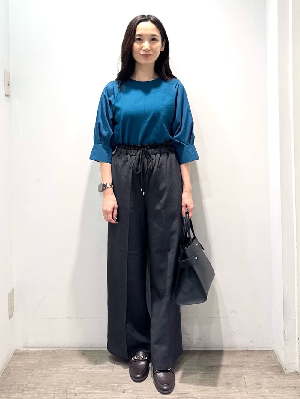 ブルー系のニット/セーター、グレー系のその他パンツ、ブラック系のショルダーバッグを着用したレディースの秋コーディネートの6枚目の写真