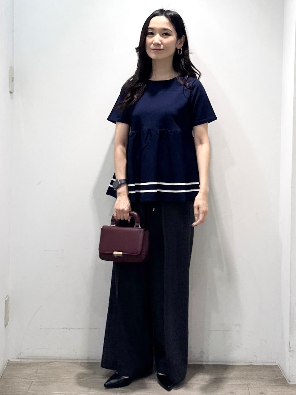 ブルー系のニット/セーター、グレー系のその他パンツ、レッド系のショルダーバッグを着用したレディースの夏コーディネートの2枚目の写真