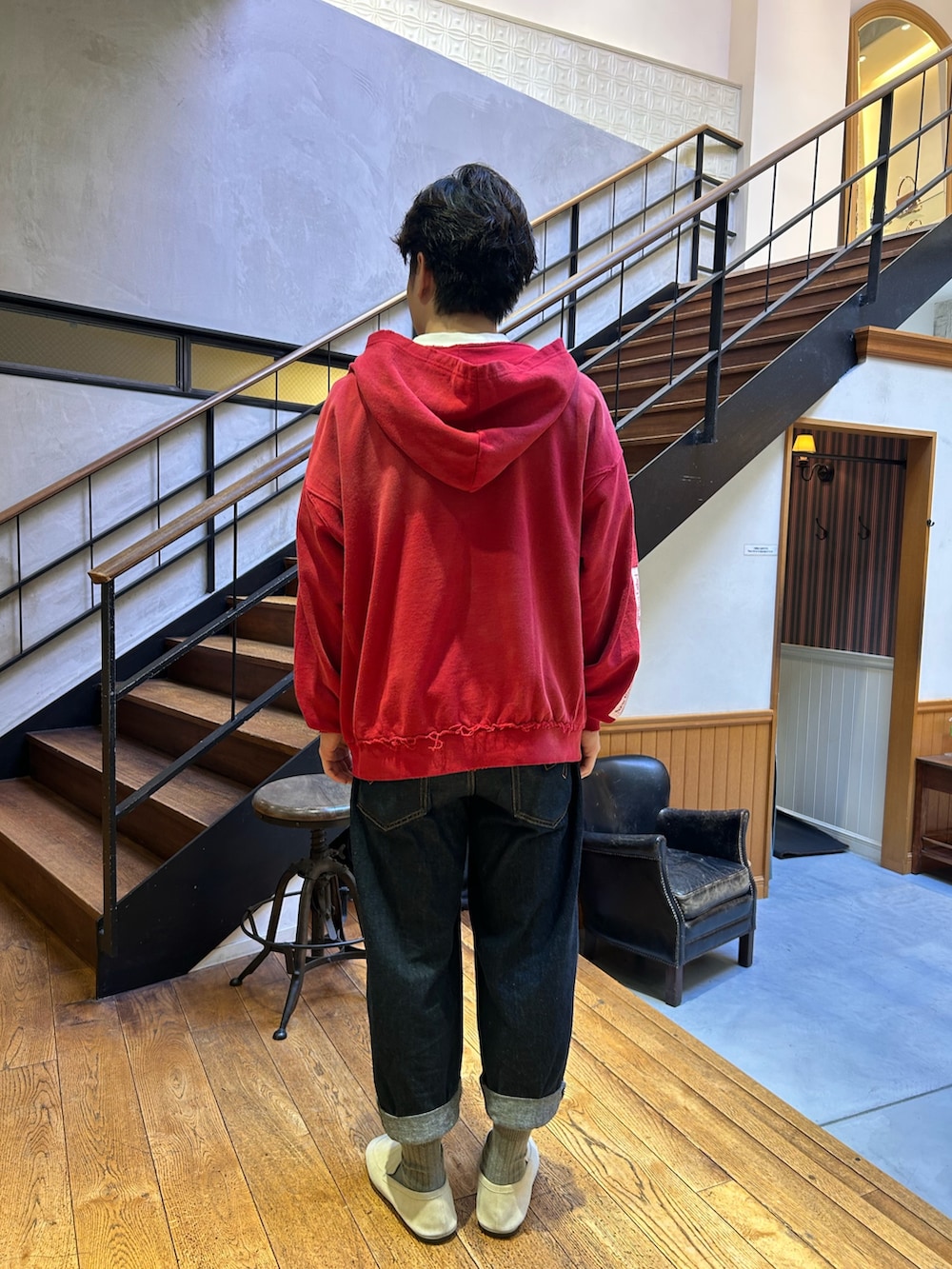 レッド系のパーカー、グレー系のデニムパンツを着用したメンズの秋コーディネートの2枚目の写真