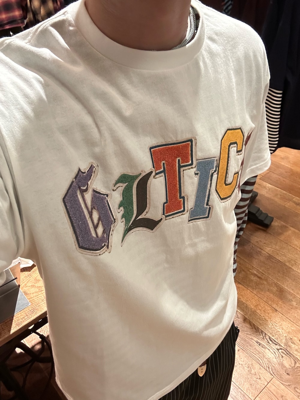 ホワイト系のTシャツ/カットソー、グリーン系のTシャツ/カットソー、ブラック系のスラックスを着用したメンズの夏コーディネートの3枚目の写真