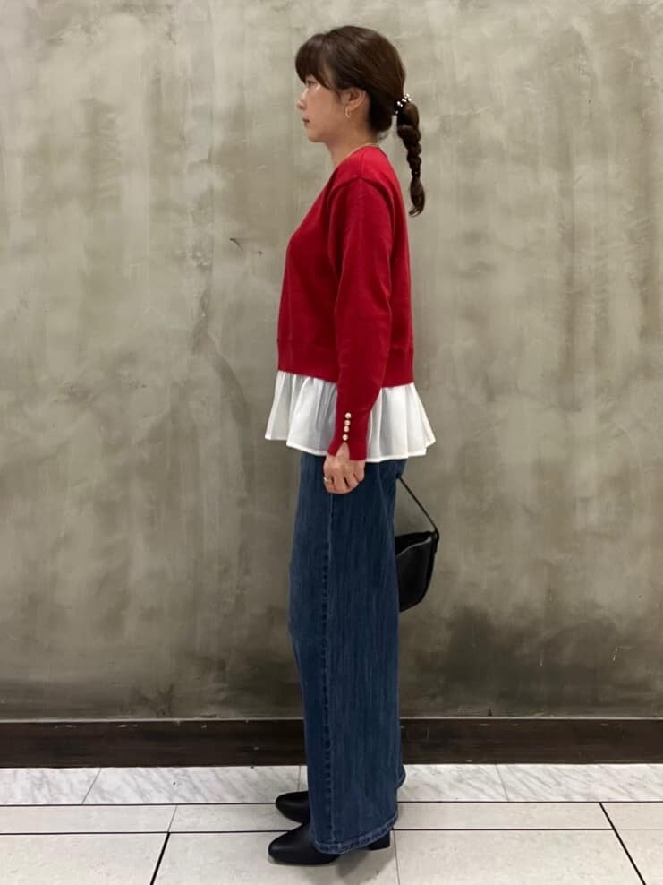 レッド系のニット/セーター、ブルー系のデニムパンツ、ブラック系のショルダーバッグを着用したレディースの秋コーディネートの2枚目の写真
