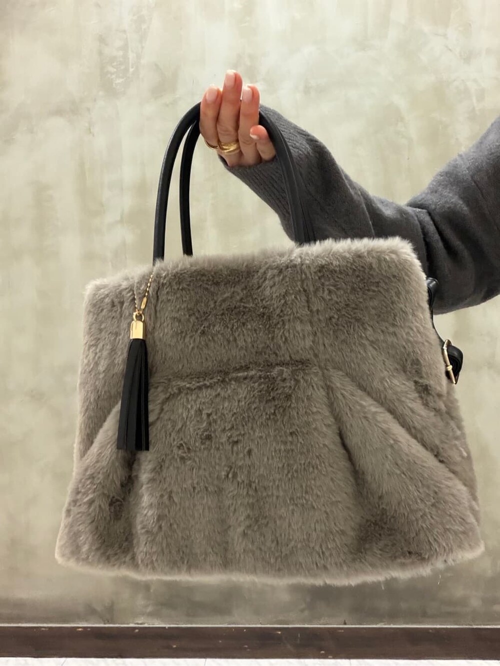 グレー系のニット/セーター、ブラック系のスカート、グレー系のトートバッグを着用したレディースの冬コーディネートの6枚目の写真