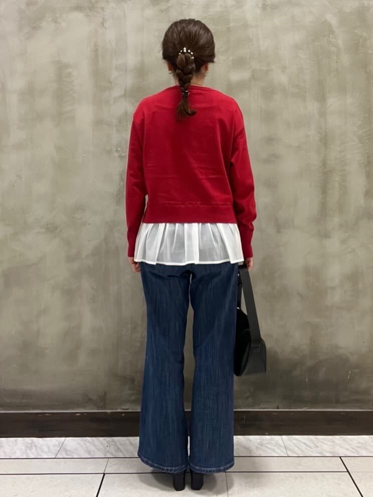 レッド系のニット/セーター、ブルー系のデニムパンツ、ブラック系のショルダーバッグを着用したレディースの秋コーディネートの3枚目の写真
