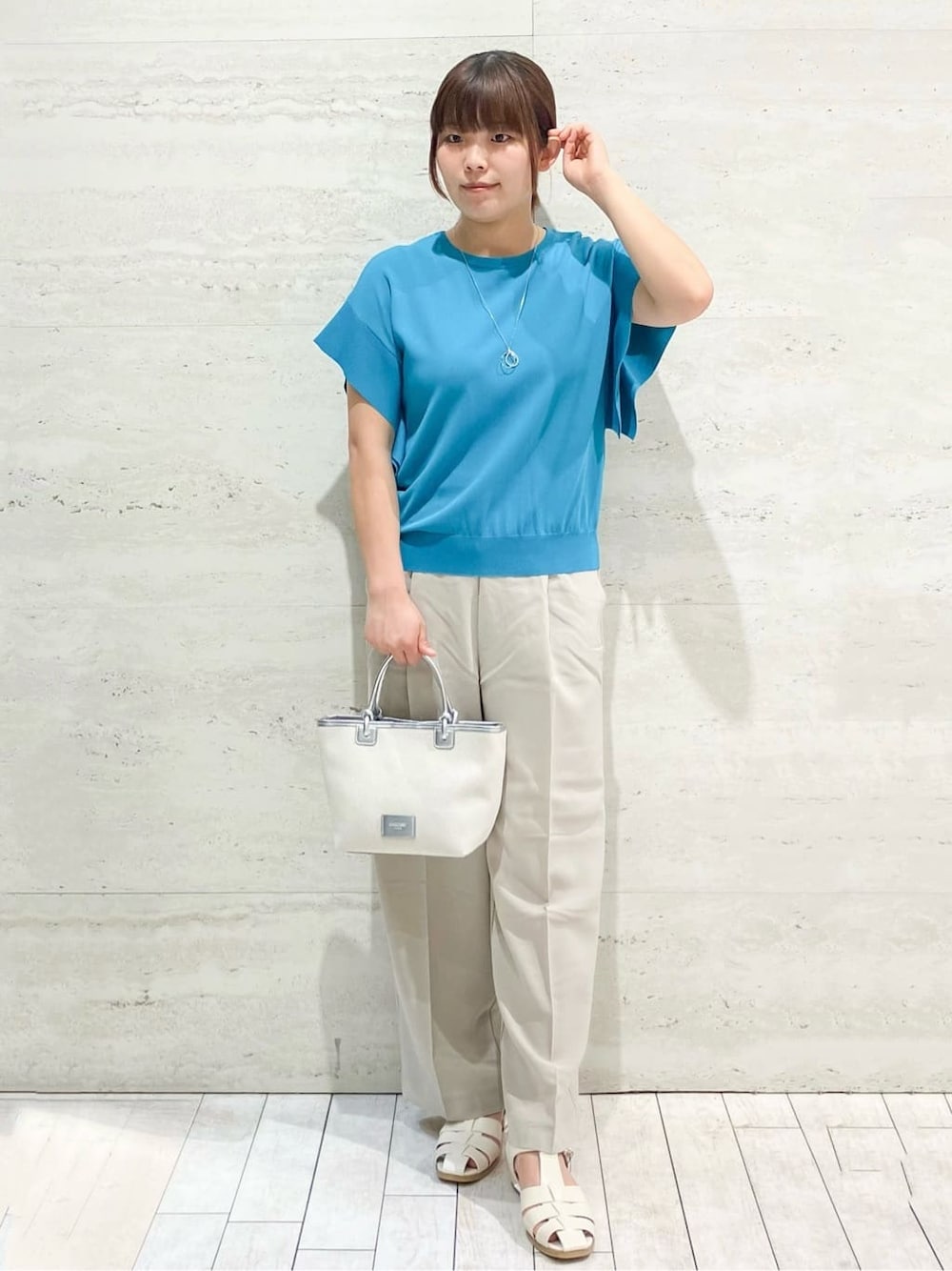 ブルー系のニット/セーター、ベージュ系のその他パンツ、シルバー系のトートバッグを着用したレディースの夏コーディネートの2枚目の写真