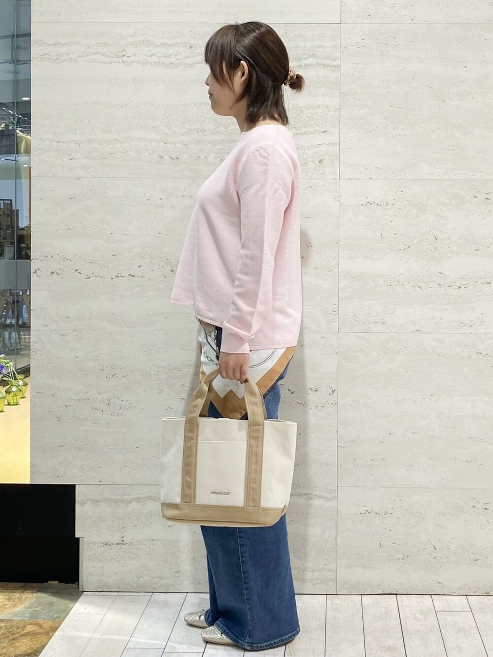 ピンク系のニット/セーター、ブルー系のデニムパンツ、ベージュ系のトートバッグを着用したレディースの春コーディネートの2枚目の写真