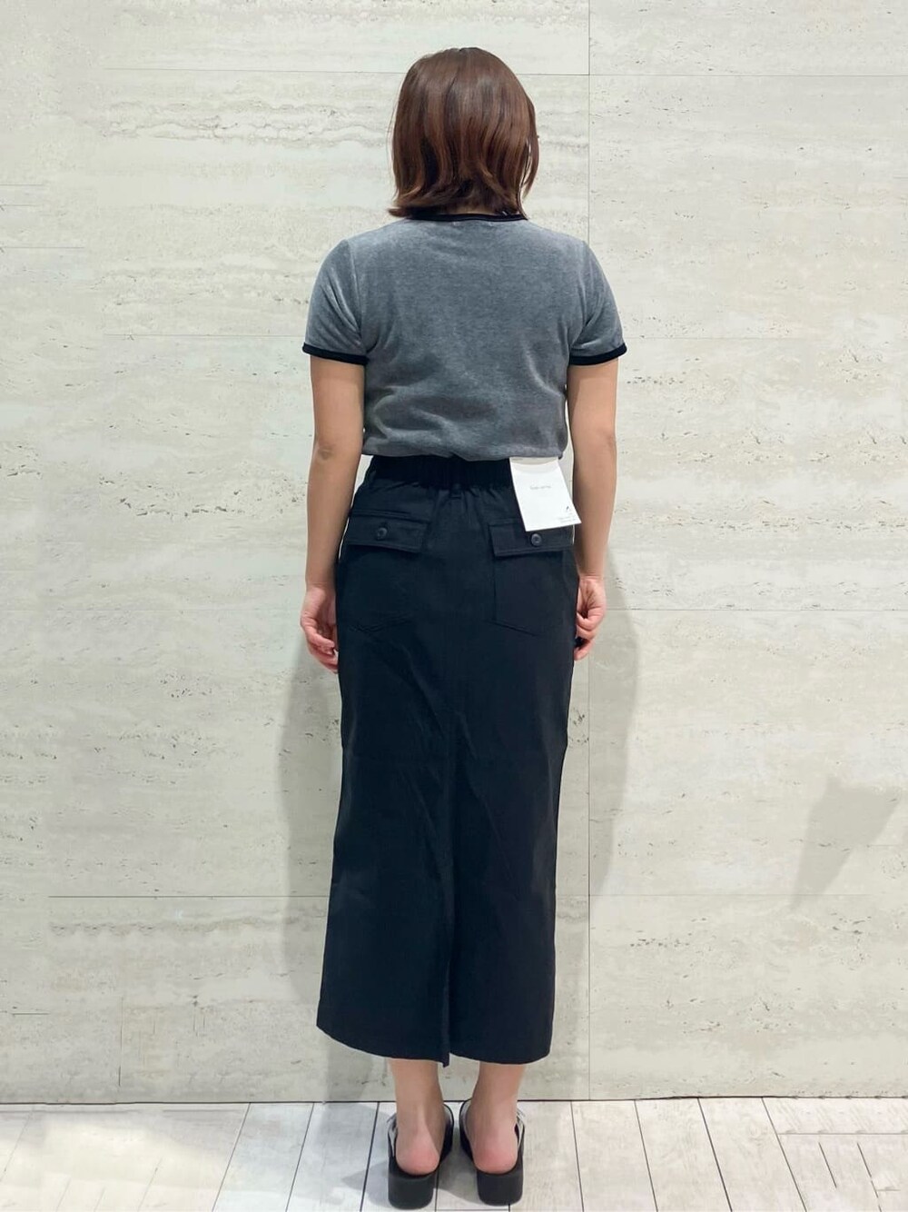 グレー系のTシャツ/カットソー、ブラック系のスカート、シルバー系のサンダルを着用したレディースの春コーディネートの2枚目の写真