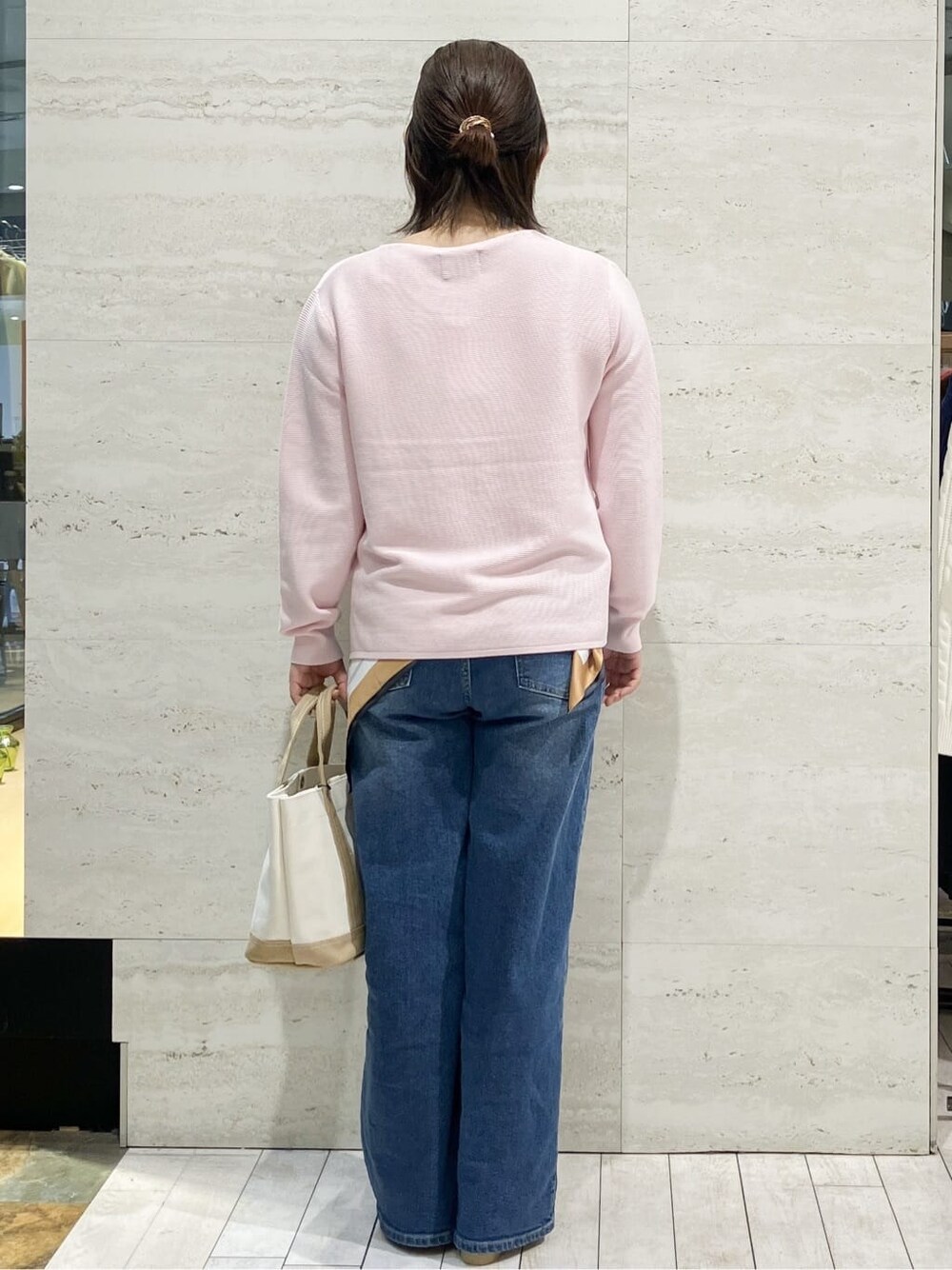 ピンク系のニット/セーター、ブルー系のデニムパンツ、ベージュ系のトートバッグを着用したレディースの春コーディネートの3枚目の写真