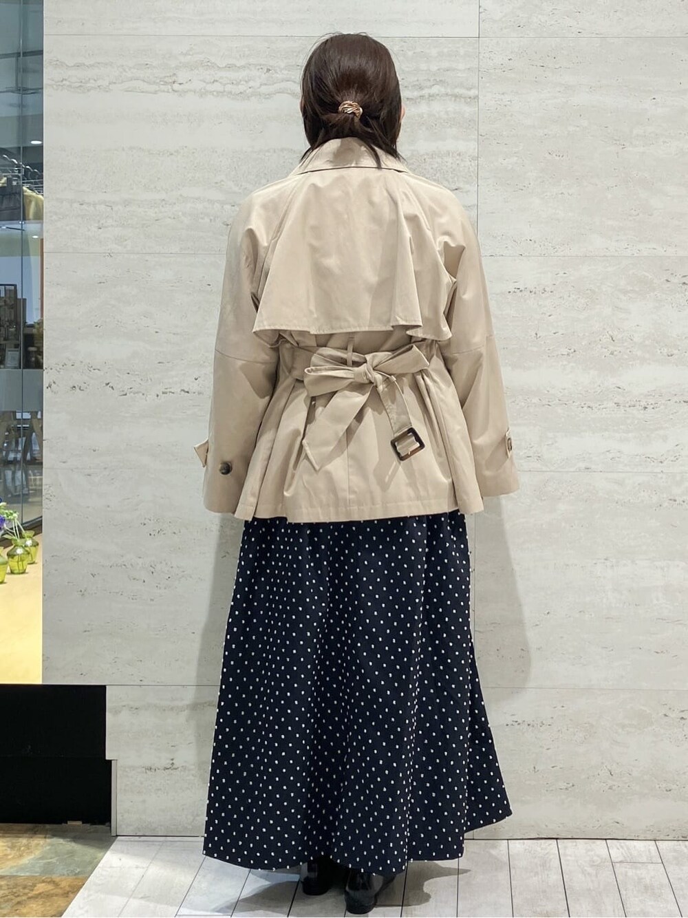ベージュ系のトレンチコート、ブラック系のニット/セーター、ブラック系のスカートを着用したレディースの春コーディネートの3枚目の写真