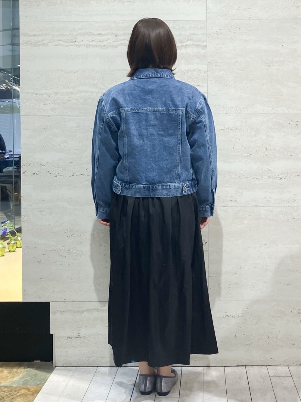 ブルー系のデニムジャケット、ホワイト系のニット/セーター、ブラック系のスカートを着用したレディースの春コーディネートの3枚目の写真