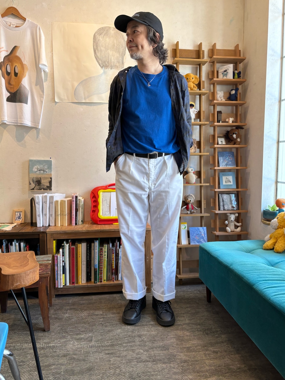 ブルー系のTシャツ/カットソー、ホワイト系のスラックス、ブラック系のスニーカーを着用したメンズの夏コーディネートの2枚目の写真