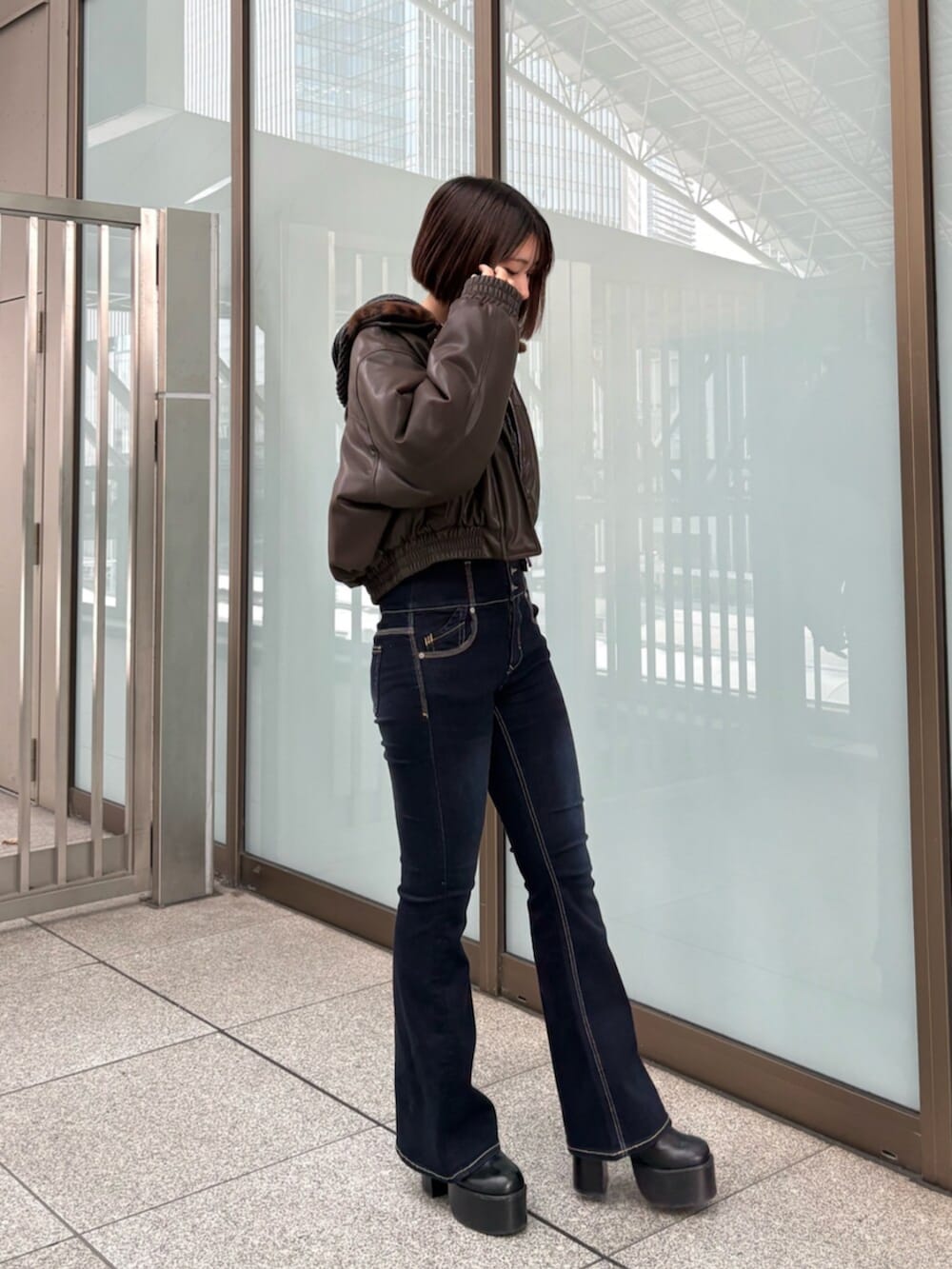 ブラウン系のブルゾン、ブラック系のデニムパンツ、ブラック系のニット/セーターを着用したレディースの冬コーディネートの2枚目の写真