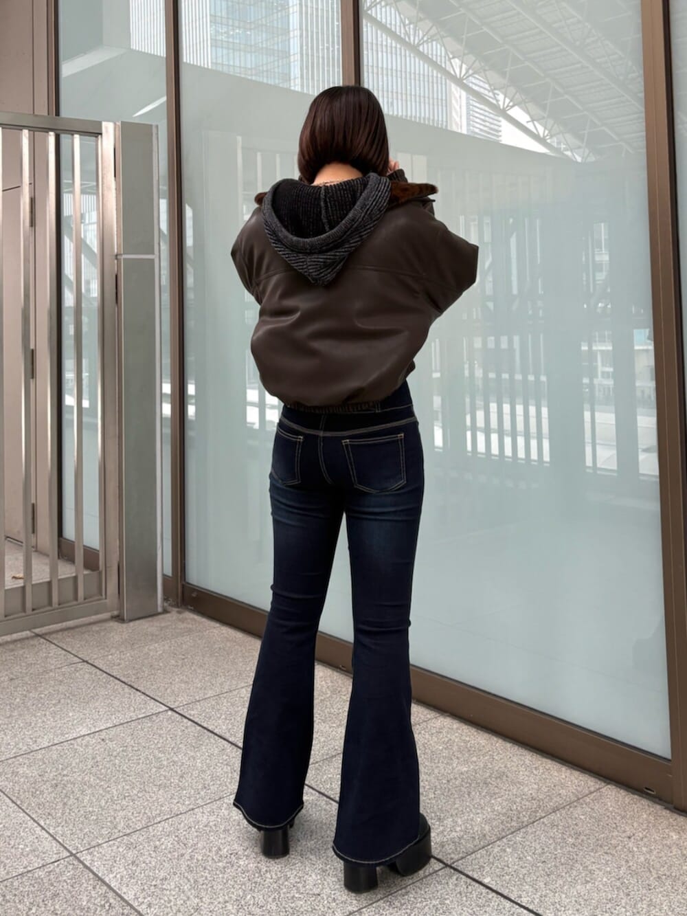 ブラウン系のブルゾン、ブラック系のデニムパンツ、ブラック系のニット/セーターを着用したレディースの冬コーディネートの4枚目の写真