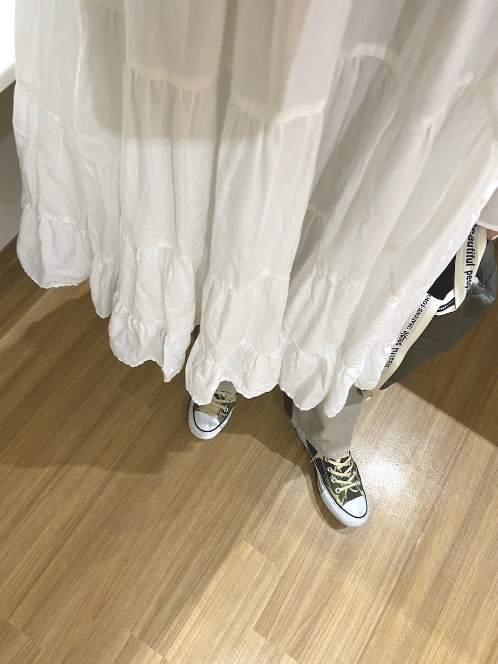 ホワイト系のワンピース、グレー系のパンツ、その他のスニーカーを着用したレディースの春コーディネートの2枚目の写真