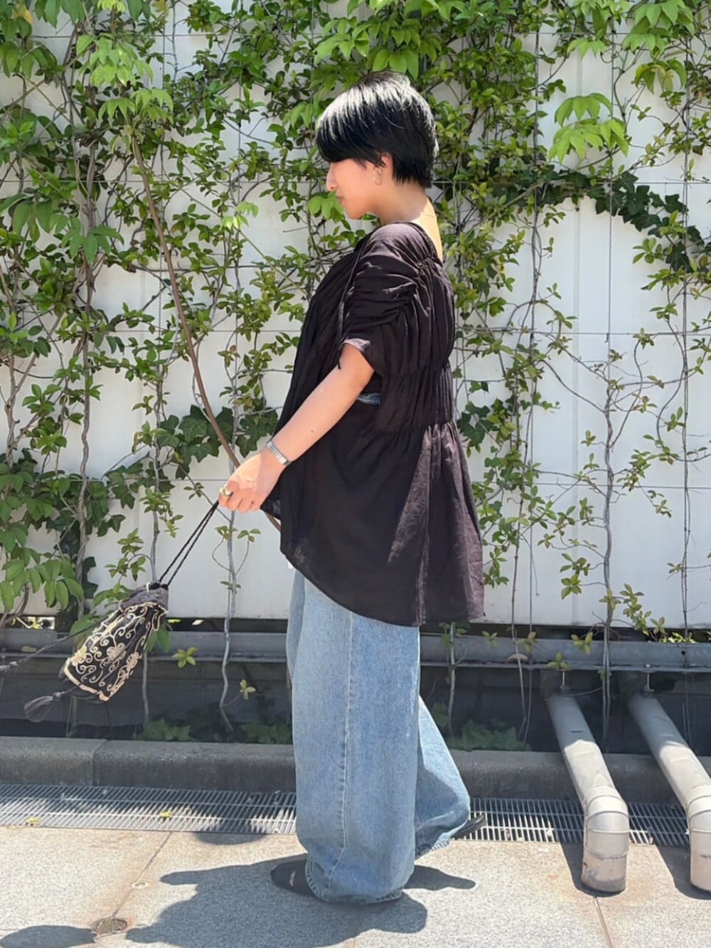 ブラック系のハンドバッグ、ブルー系のデニムパンツ、ブラック系のシャツ/ブラウスを着用したレディースの夏コーディネートの2枚目の写真