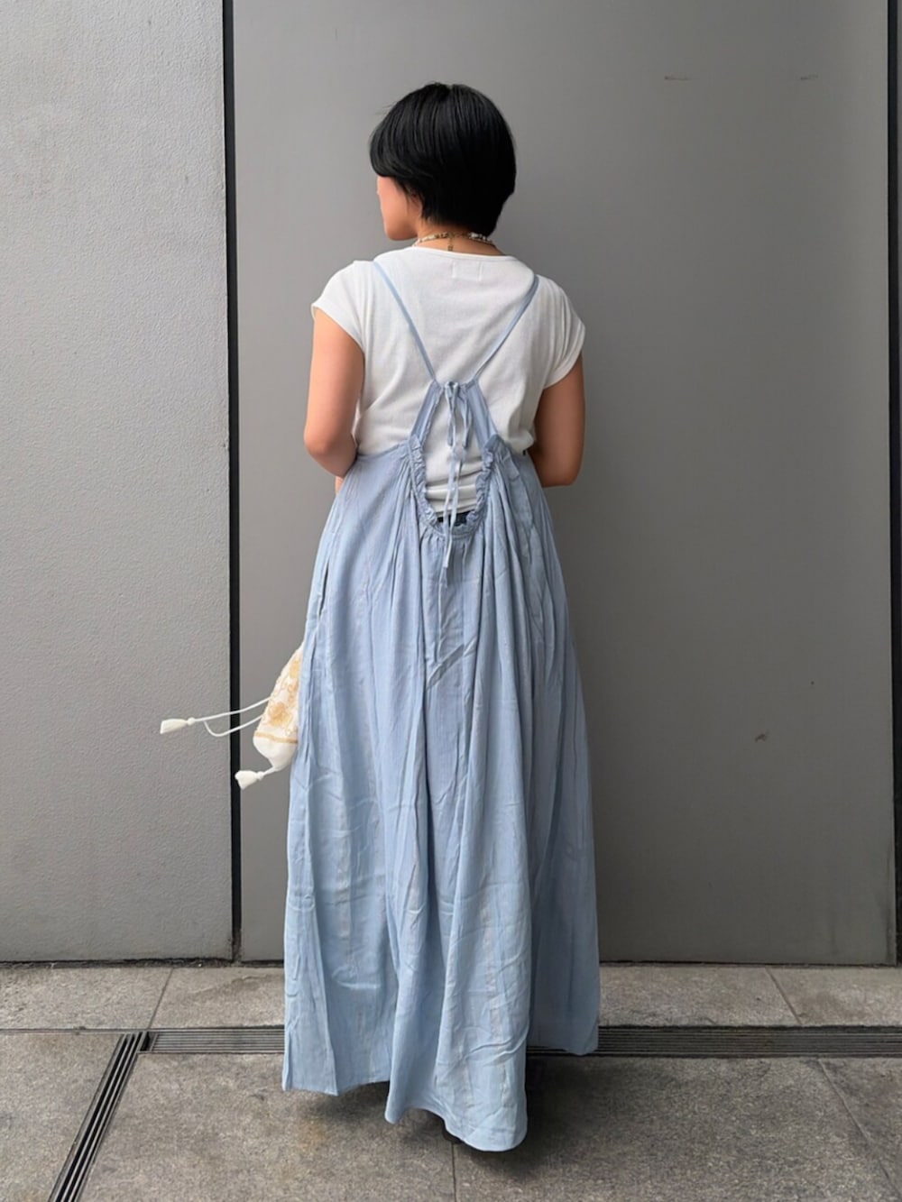 ブラック系のハンドバッグ、ブルー系のワンピース、ホワイト系のTシャツ/カットソーを着用したレディースの夏コーディネートの3枚目の写真