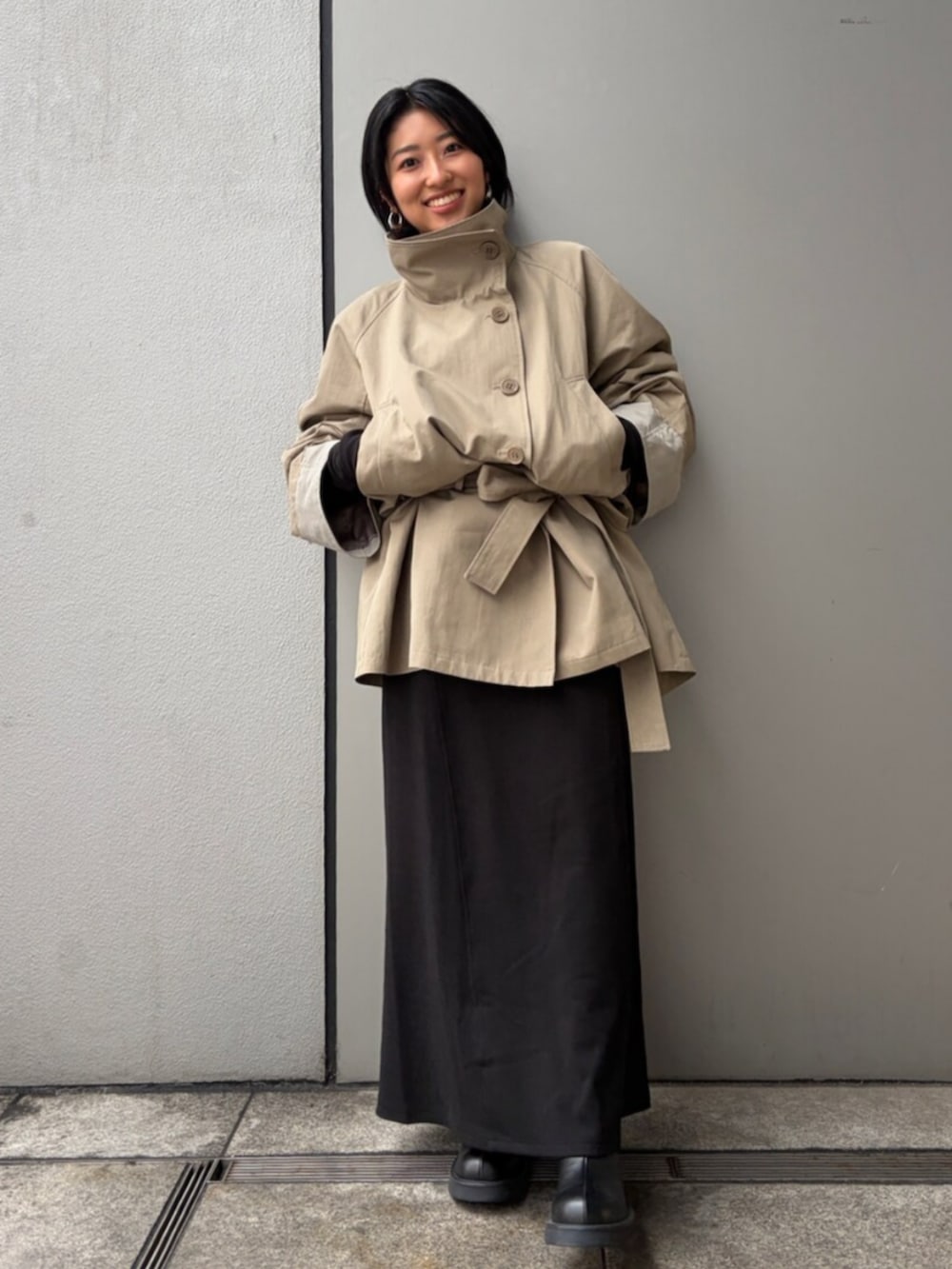 ブラック系のワンピース、グリーン系のトレンチコートを着用したレディースの春コーディネートの4枚目の写真