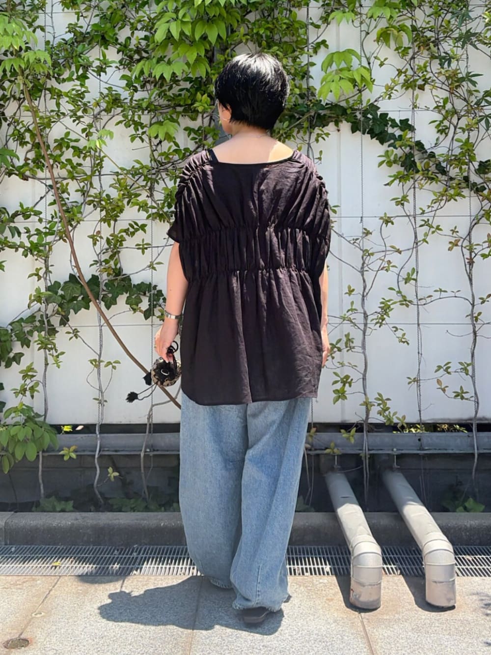 ブラック系のハンドバッグ、ブルー系のデニムパンツ、ブラック系のシャツ/ブラウスを着用したレディースの夏コーディネートの3枚目の写真