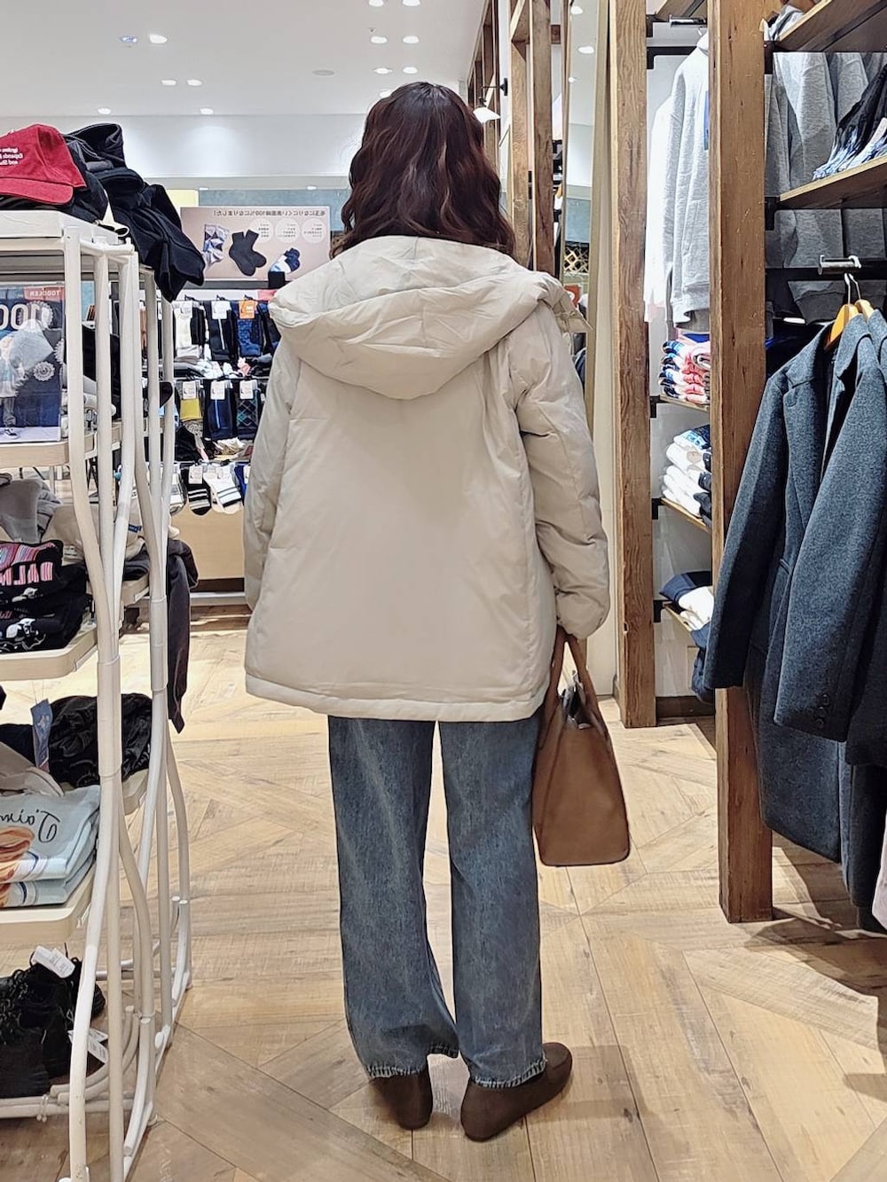 ベージュ系のダウンジャケット/コート、ブルー系のデニムパンツ、ベージュ系のショルダーバッグを着用したレディースの秋コーディネートの2枚目の写真