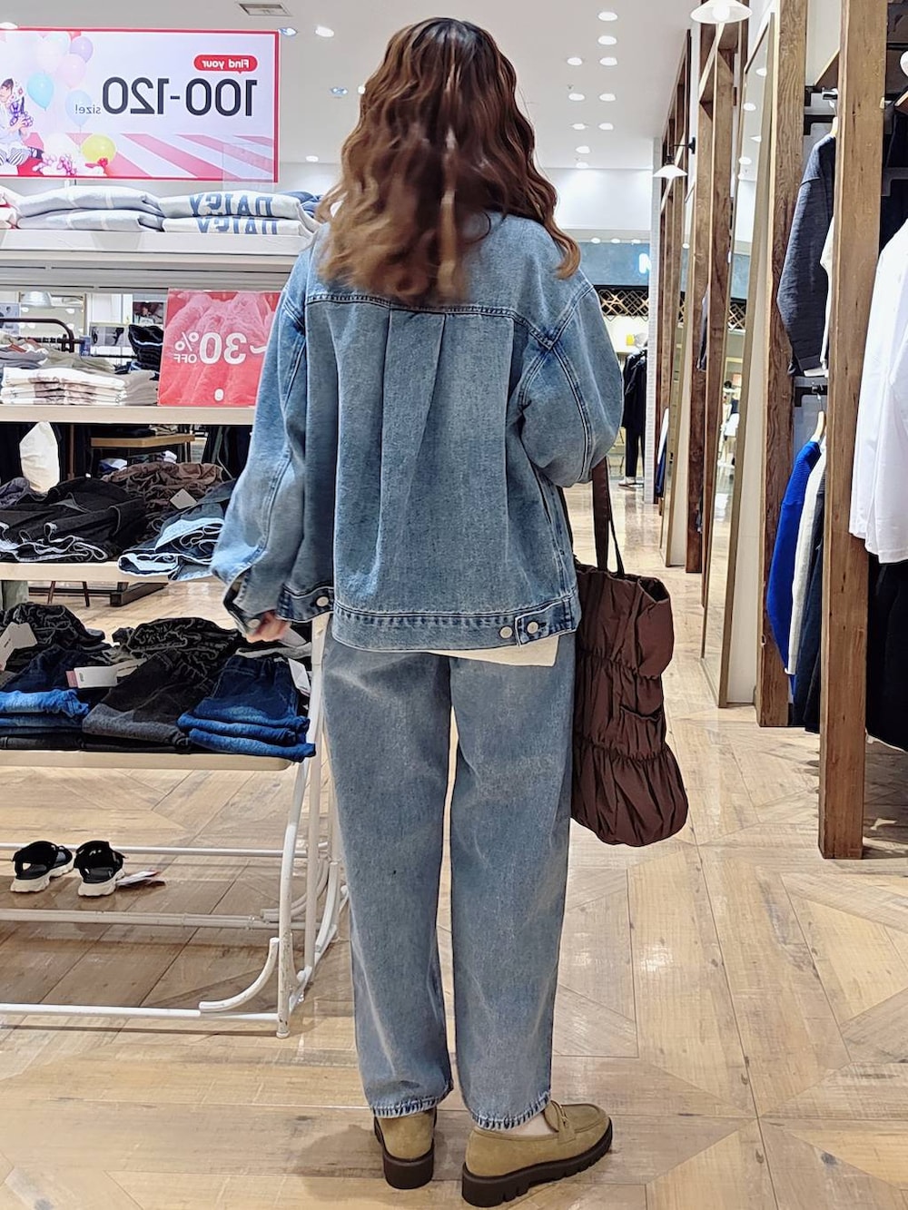ブラウン系のトートバッグ、ブルー系のデニムパンツ、ブルー系のデニムジャケットを着用したレディースの秋コーディネートの2枚目の写真
