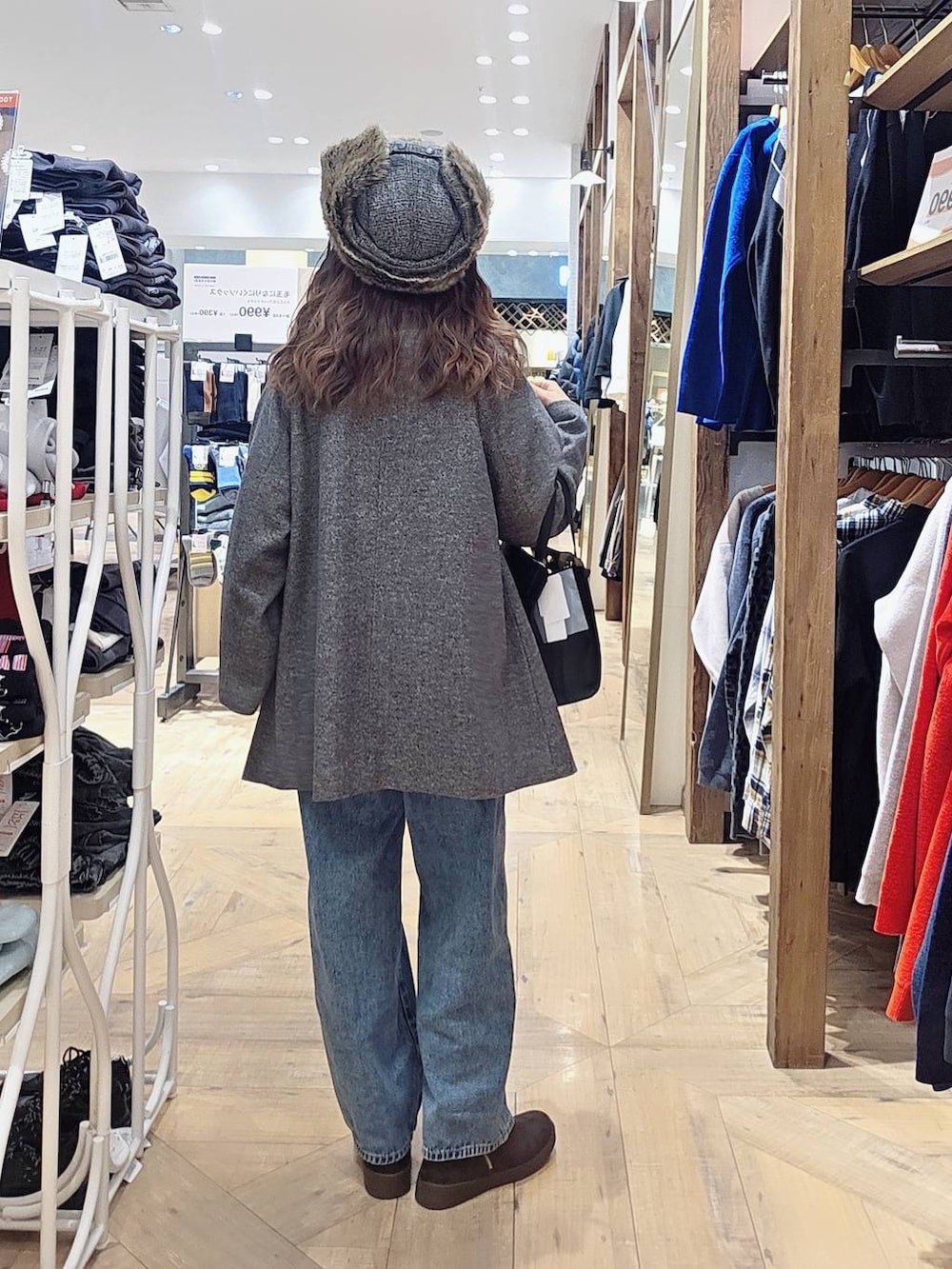 ブラック系のショルダーバッグ、ブルー系のデニムパンツ、グレー系のチェスターコートを着用したレディースの冬コーディネートの2枚目の写真