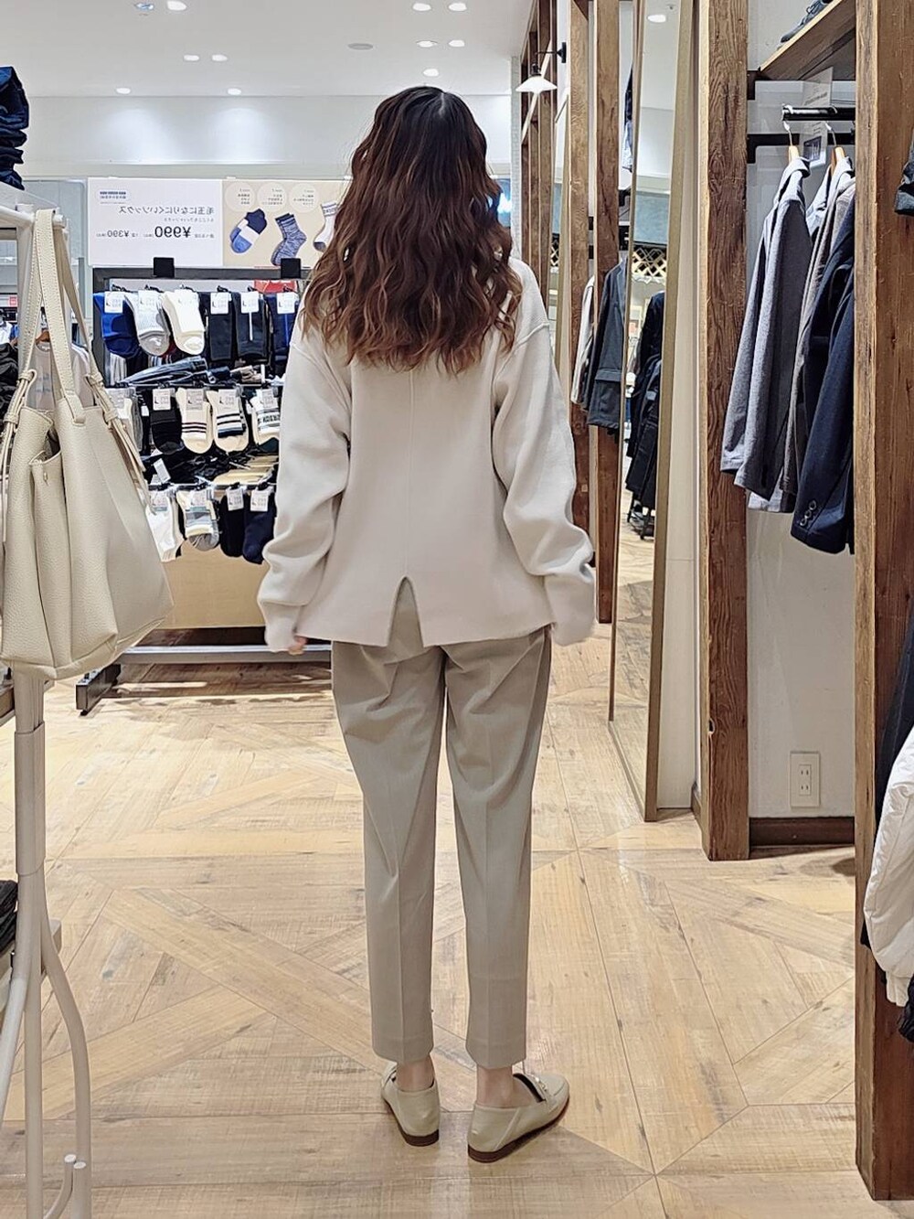 ブラック系のマウンテンパーカー、ベージュ系のスラックス、ホワイト系のニット/セーターを着用したレディースの冬コーディネートの4枚目の写真