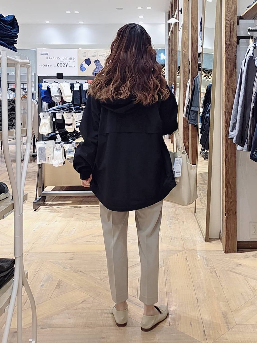 ブラック系のマウンテンパーカー、ベージュ系のスラックス、ホワイト系のニット/セーターを着用したレディースの冬コーディネートの2枚目の写真