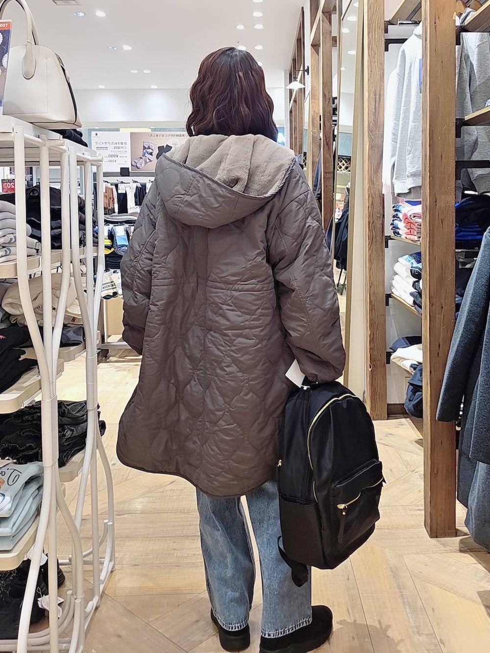 ブルー系のデニムパンツ、ブラウン系のブルゾン、ブラック系のバックパック/リュックを着用したレディースの秋コーディネートの2枚目の写真