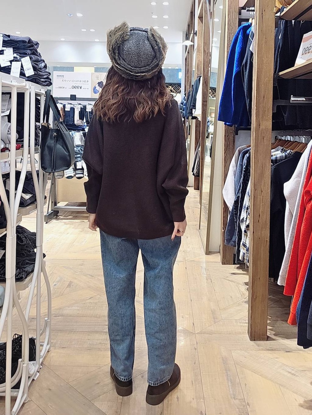 ブラック系のショルダーバッグ、ブルー系のデニムパンツ、グレー系のチェスターコートを着用したレディースの冬コーディネートの4枚目の写真