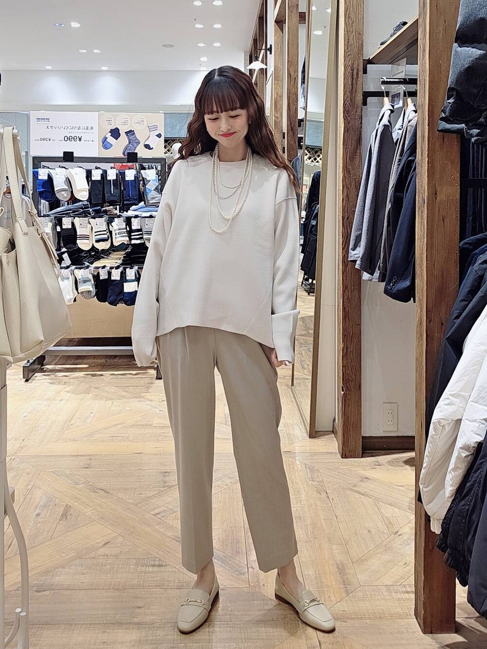 ブラック系のマウンテンパーカー、ベージュ系のスラックス、ホワイト系のニット/セーターを着用したレディースの冬コーディネートの3枚目の写真