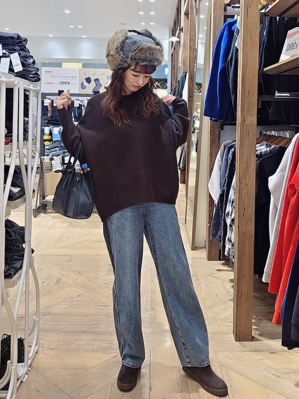 ブラック系のショルダーバッグ、ブルー系のデニムパンツ、グレー系のチェスターコートを着用したレディースの冬コーディネートの3枚目の写真