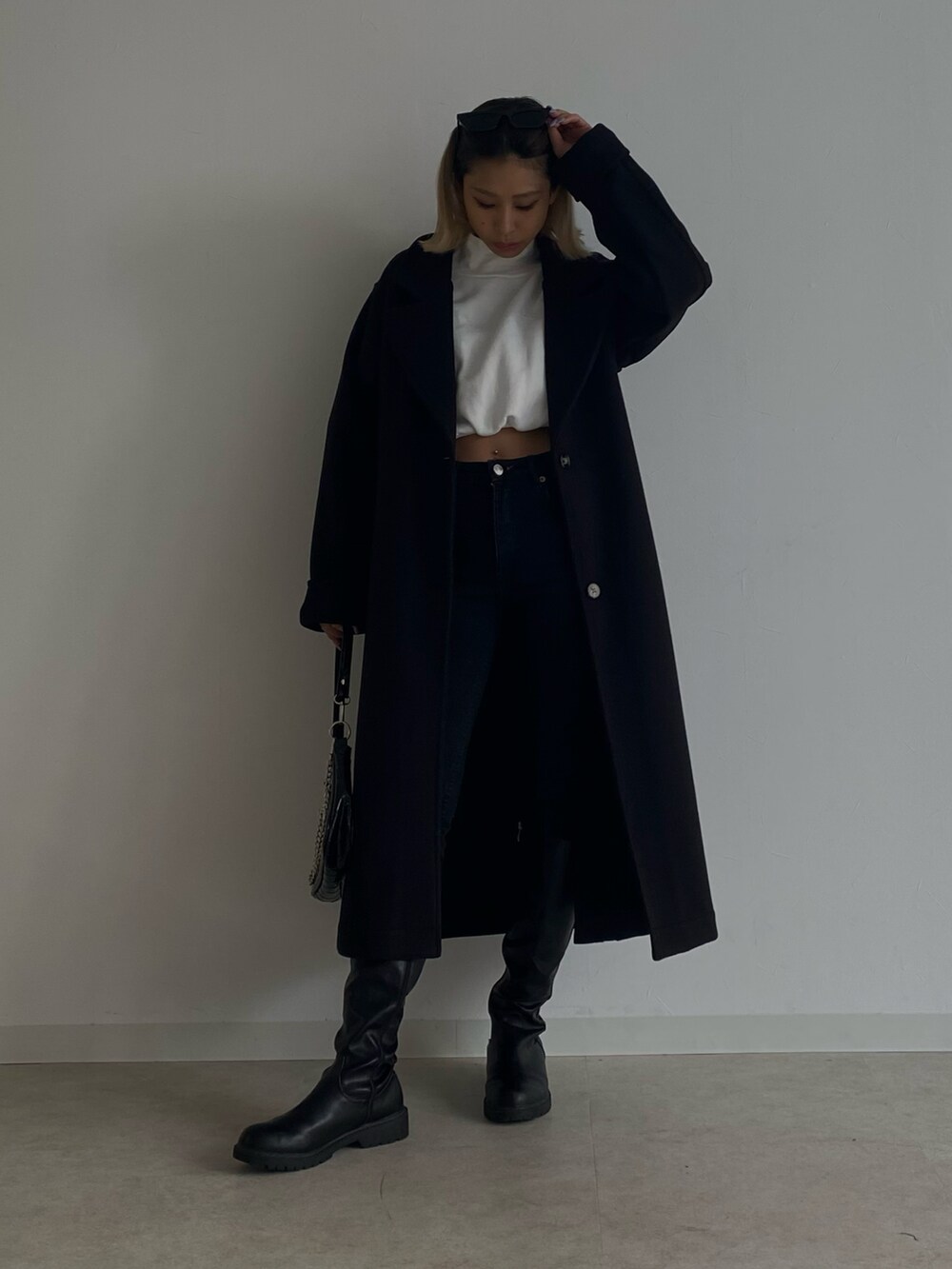 ブラック系のデニムパンツ、ブラック系のチェスターコート、ホワイト系のTシャツ/カットソーを着用したレディースの冬コーディネートの2枚目の写真