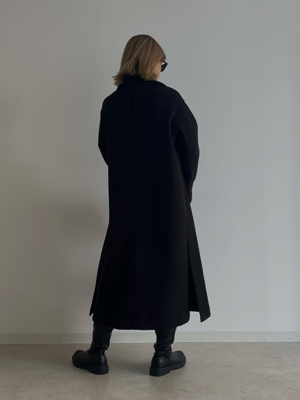 ブラック系のデニムパンツ、ブラック系のチェスターコート、ホワイト系のTシャツ/カットソーを着用したレディースの冬コーディネートの3枚目の写真