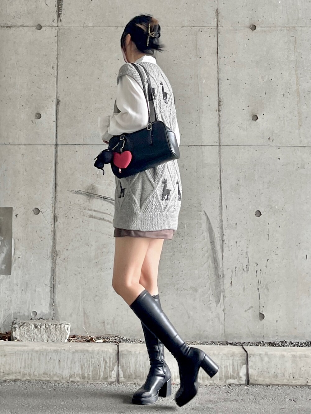 ブラック系のブーツ、ブラウン系のパンツ、グレー系のベストを着用したレディースの秋コーディネートの2枚目の写真