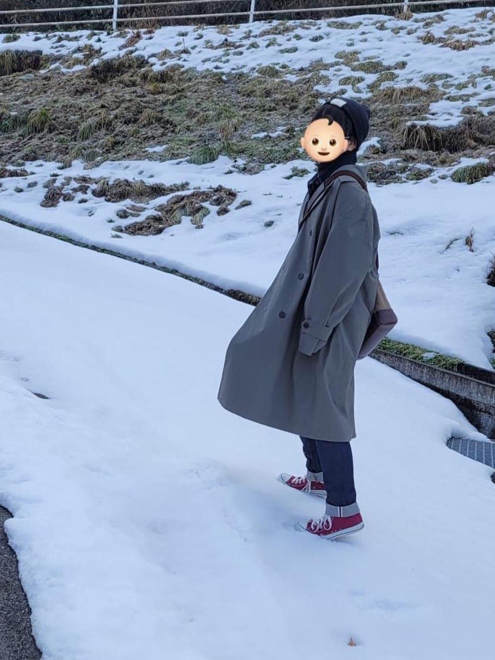 グレー系のトレンチコート、ブルー系のデニムジャケット、ブルー系のデニムパンツを着用したレディースの冬コーディネートの2枚目の写真