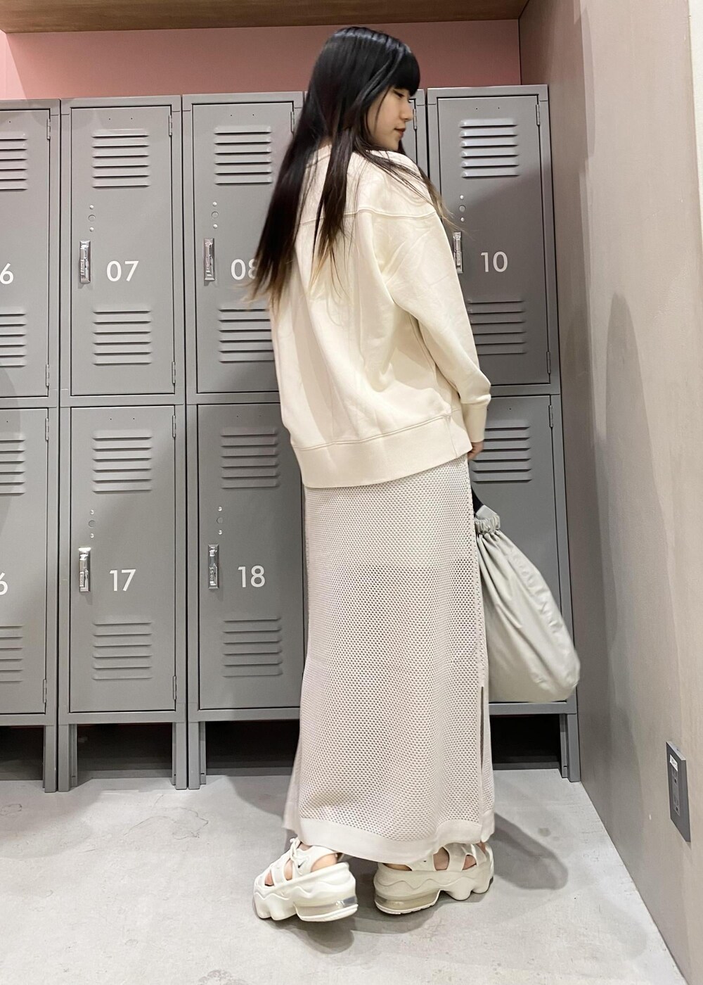 シルバー系のスカート、ホワイト系のサンダル、ベージュ系のスウェットを着用したレディースの春コーディネートの3枚目の写真