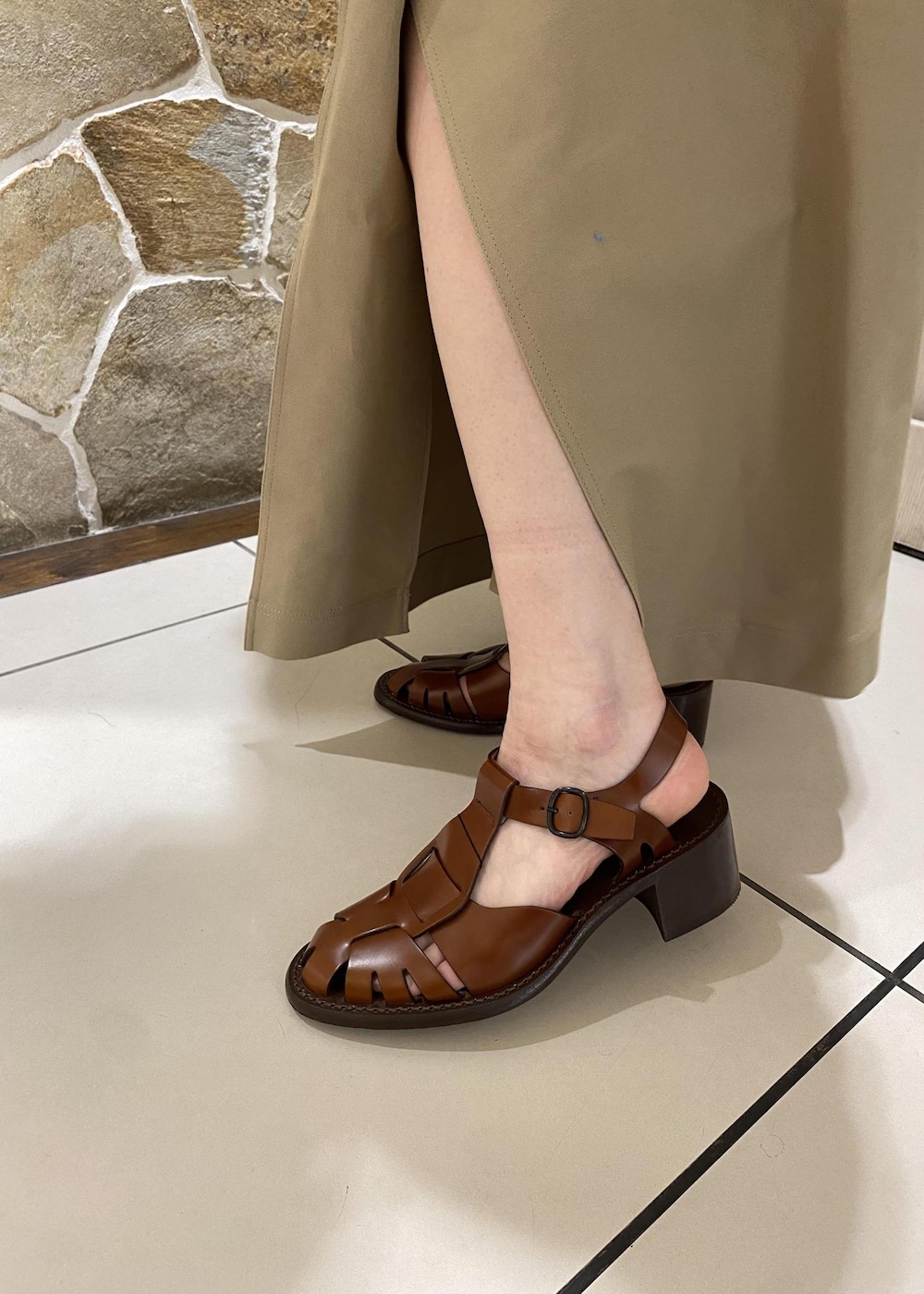 ベージュ系のショルダーバッグ、ベージュ系のスカート、ホワイト系のポロシャツを着用したレディースの春コーディネートの6枚目の写真