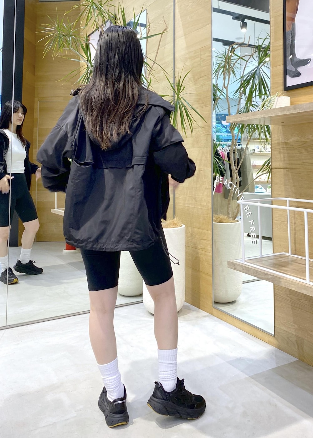 ブラック系のブルゾン、ホワイト系のタンクトップ、ブラック系のスニーカーを着用したレディースの夏コーディネートの3枚目の写真