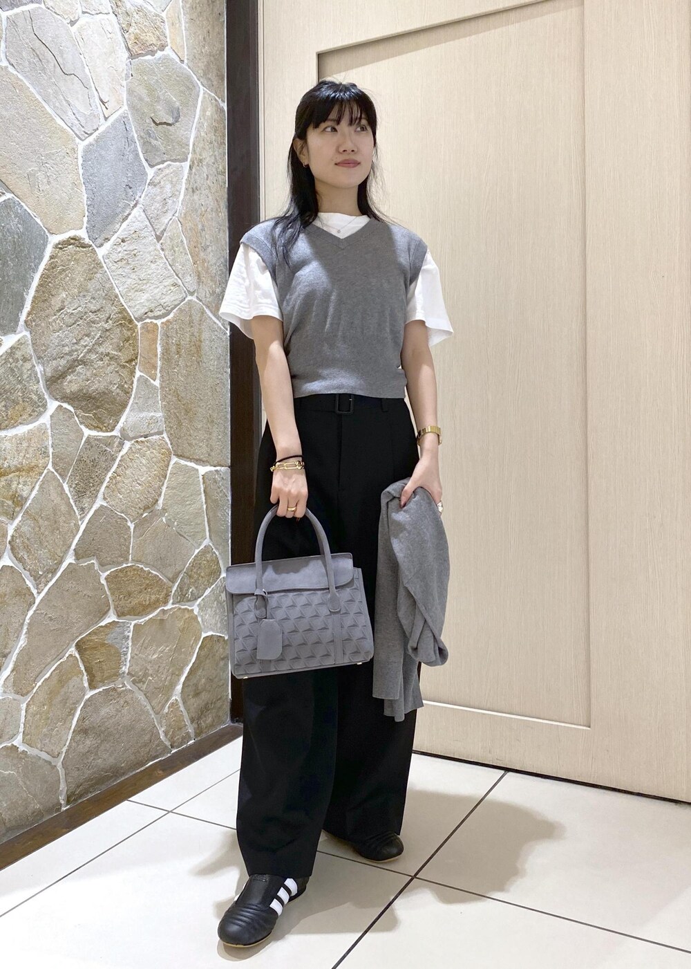 ブラック系のスニーカー、グレー系のニット/セーター、ブラック系のスラックスを着用したレディースの秋コーディネートの2枚目の写真