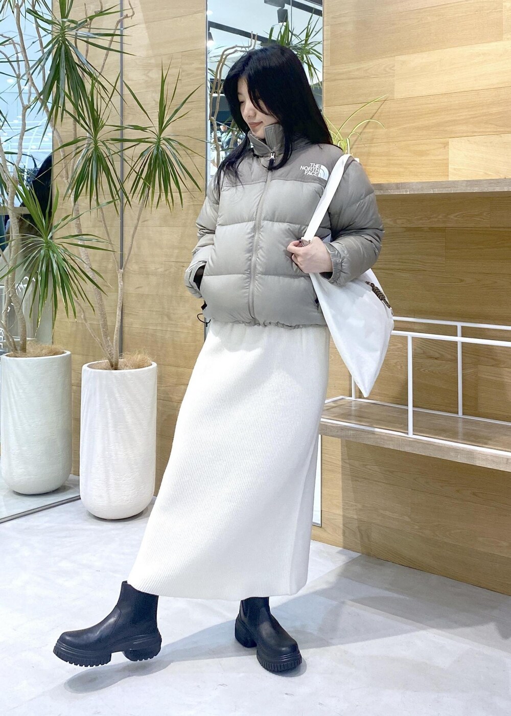 ホワイト系のトートバッグ、ベージュ系のダウンジャケット/コートを着用したレディースの秋コーディネートの3枚目の写真