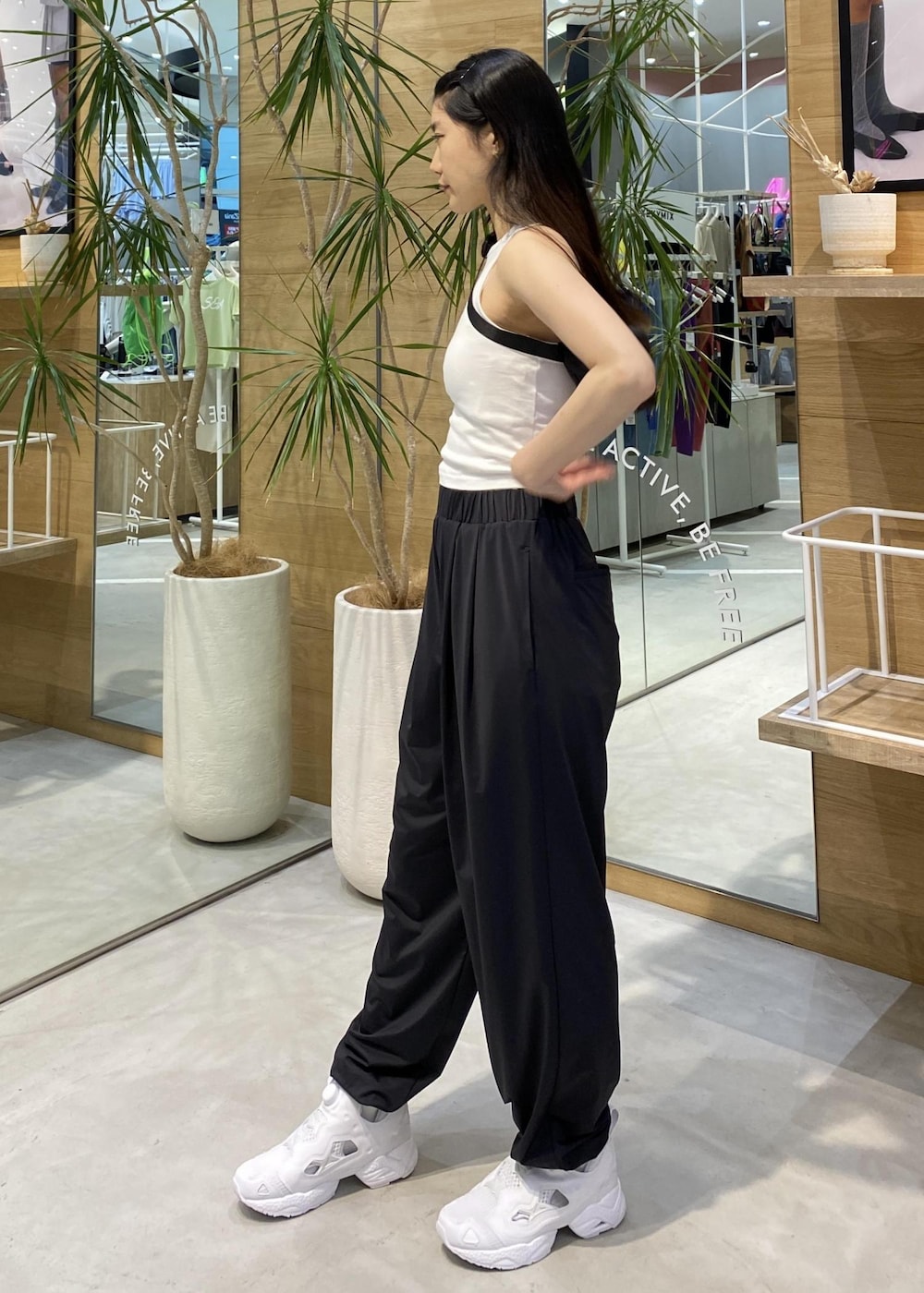 ブラック系のカーゴパンツ、ホワイト系のスニーカー、ホワイト系のタンクトップを着用したレディースの春コーディネートの3枚目の写真