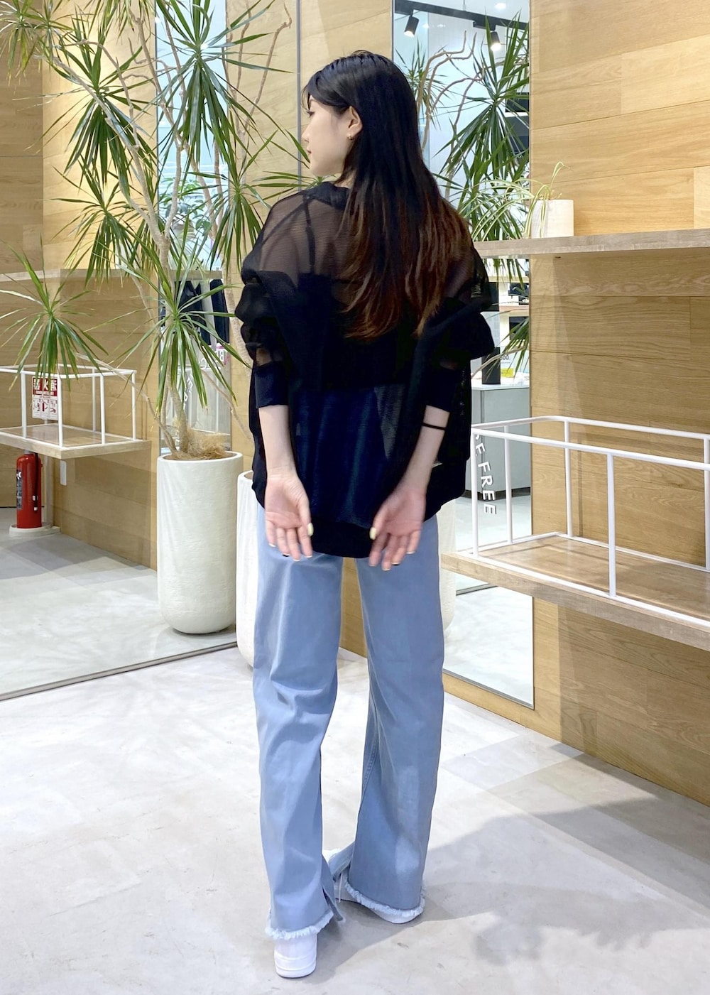ブラック系のカーディガン/ボレロ、ホワイト系のスニーカー、ブルー系のデニムパンツを着用したレディースの秋コーディネートの6枚目の写真