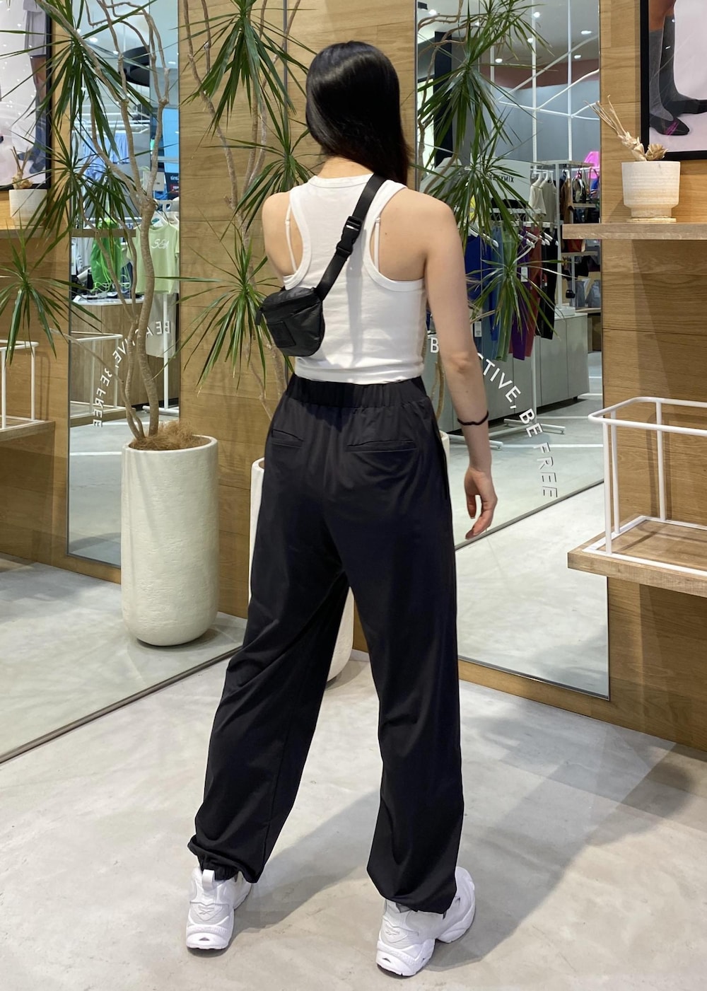 ブラック系のカーゴパンツ、ホワイト系のスニーカー、ホワイト系のタンクトップを着用したレディースの春コーディネートの5枚目の写真
