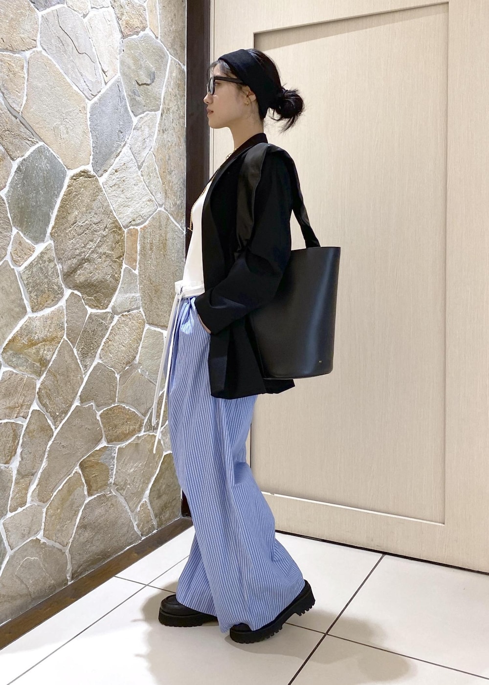 ブルー系のスラックス、ブラック系のテーラードジャケット、ブラック系のローファーを着用したレディースの秋コーディネートの3枚目の写真