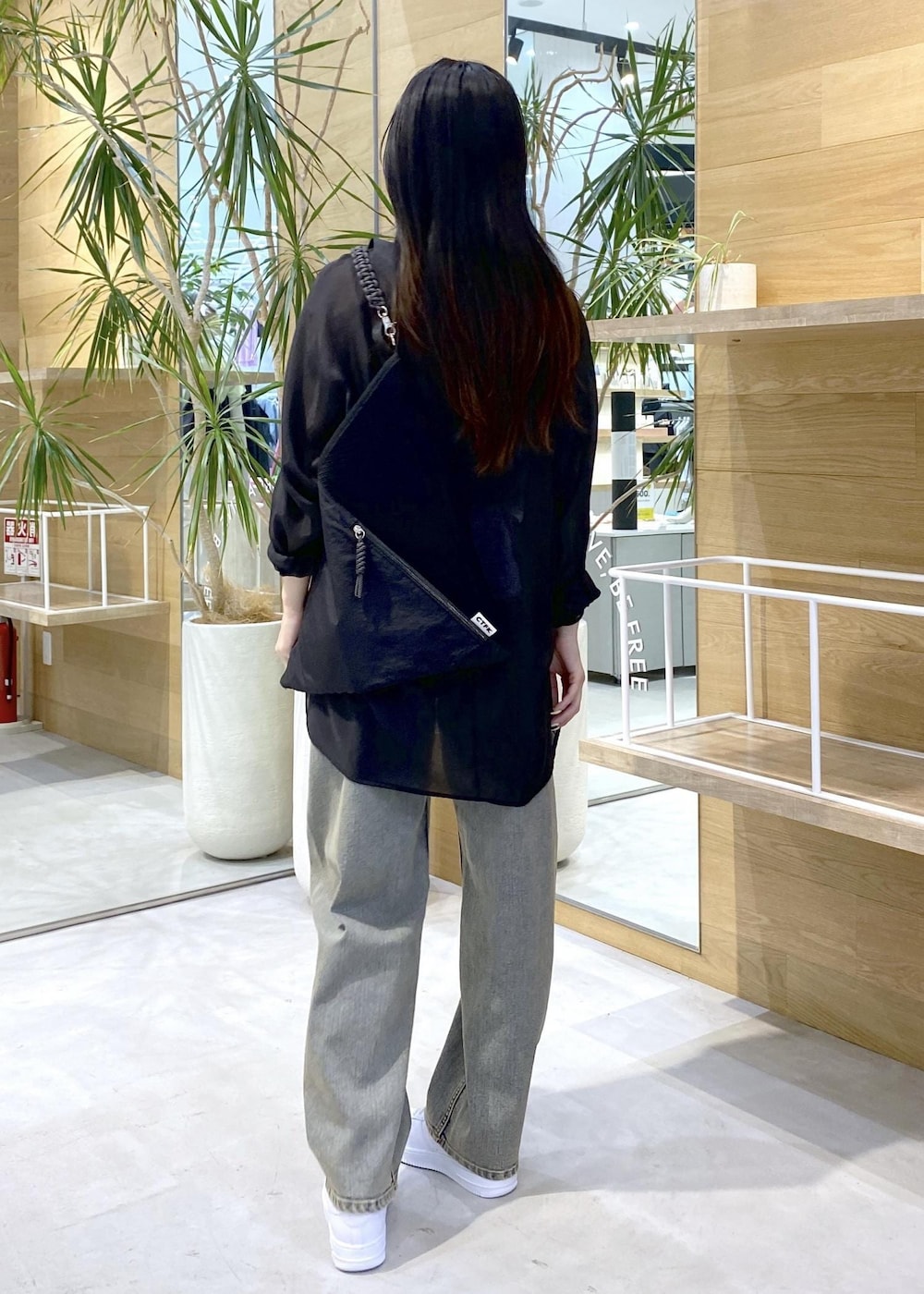 ホワイト系のスニーカー、ブラック系のキャミソール、ベージュ系のデニムパンツを着用したレディースの秋コーディネートの5枚目の写真